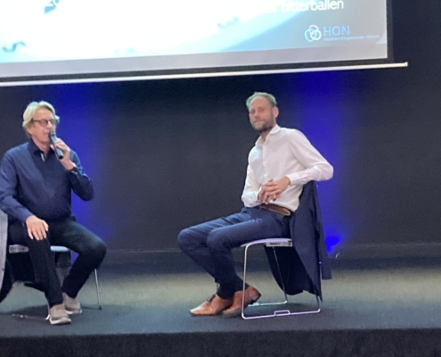 Twee mannen in gesprek op een podium