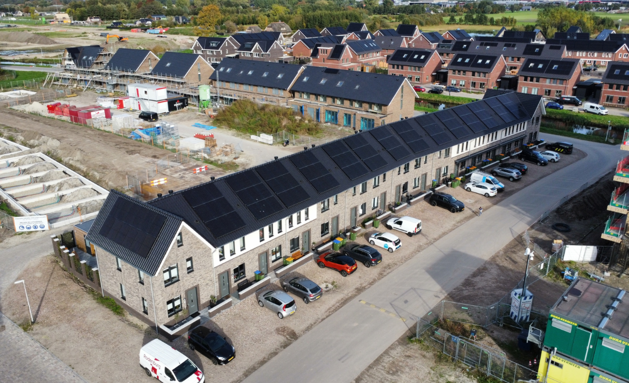 Lange rij nieuwbouwwoningen met zonnepanelen op het dak in een wijk