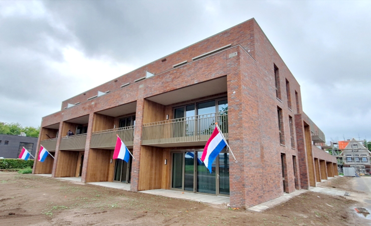 Bakstenen appartementencomplex met balkons en Nederlandse vlaggen buiten. Bakstenen appartementencomplex met balkons en Nederlandse vlaggen buiten.
