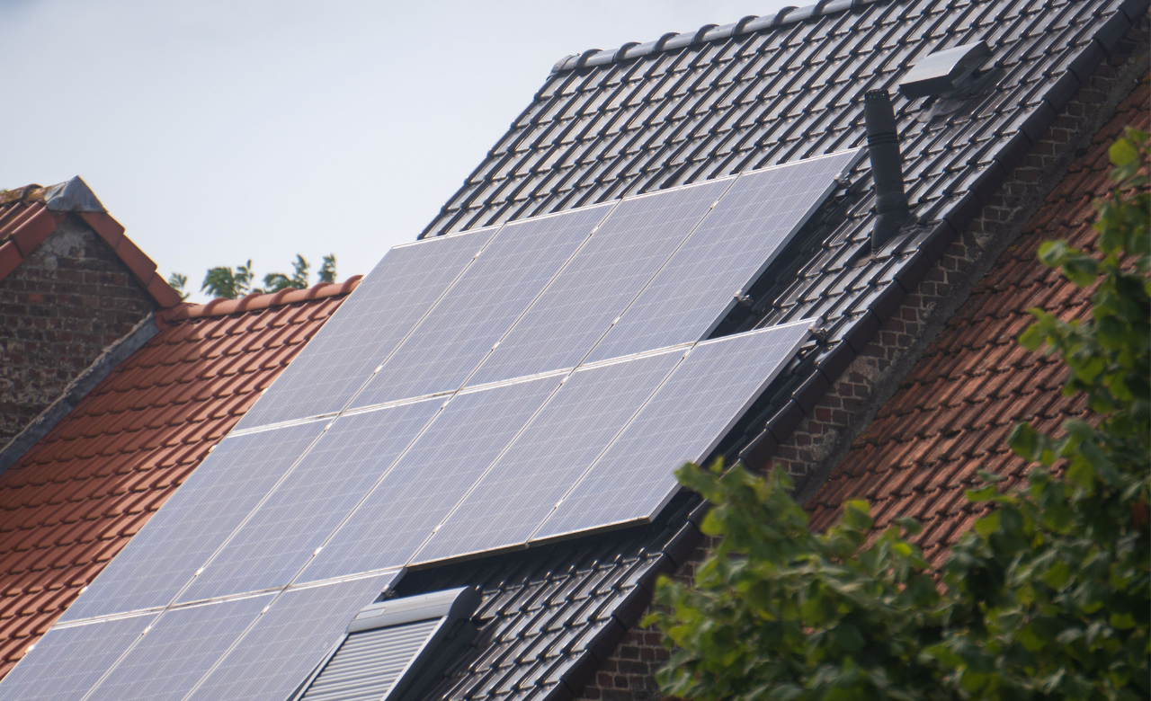 Een rijtjeshuis met rood dak met daarop zonnepanelen voor duurzame energie.